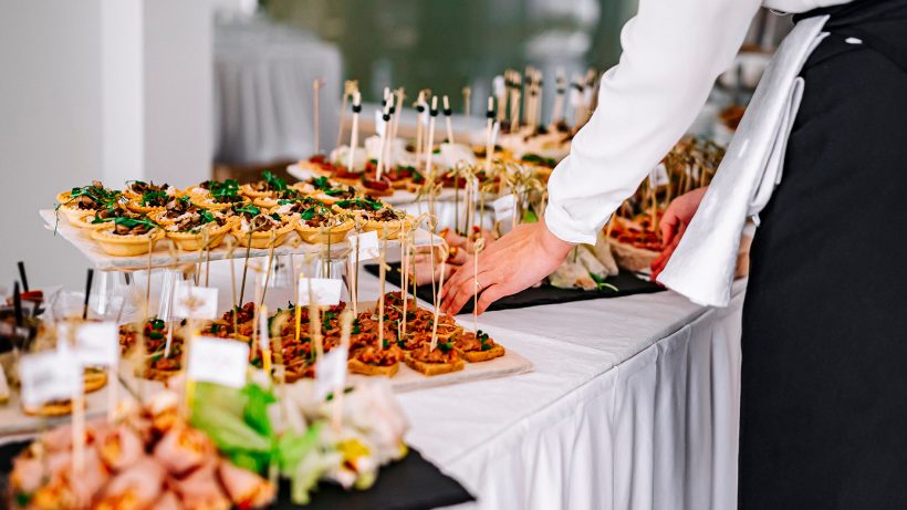 woman hands of a waiter prepare food for a buffet table in a restaurant